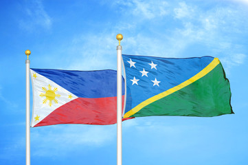 Philippines and Solomon Islands two flags on flagpoles and blue cloudy sky