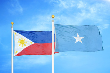 Philippines and Somalia two flags on flagpoles and blue cloudy sky