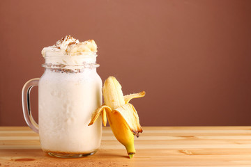 banan Milkshake with Cinnamon on wooden table and brown background closeup, copy space. Banana cinnamon smoothie with peanut butter and oats in glass. Healthy breakfast concept