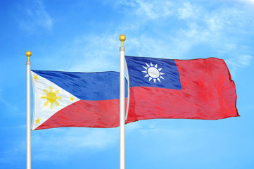 Philippines and Taiwan two flags on flagpoles and blue cloudy sky