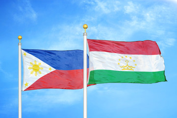Philippines and Tajikistan two flags on flagpoles and blue cloudy sky