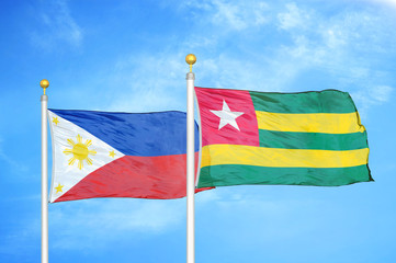 Philippines and Togo two flags on flagpoles and blue cloudy sky