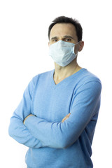 Coronavirus 2019-ncov covid-19 concept. A middle-aged man with arms crossed on his chest is standing in the studio in a protective medical mask in order to be safe from viruses and infections.