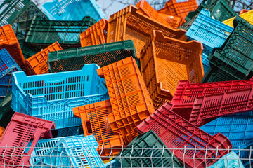 Old plastic boxes in a warehouse as a trash behind the metal mesh fence.