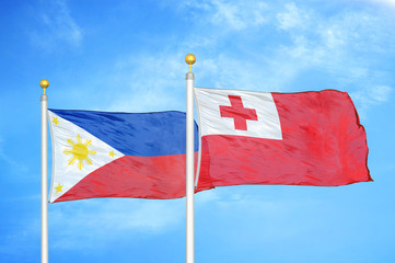 Philippines and Tonga two flags on flagpoles and blue cloudy sky