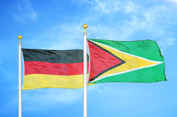 Germany and Guyana two flags on flagpoles and blue cloudy sky