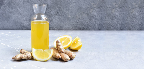 Ginger-lemon drink in a bottle, ingredients of ginger cocktail or tea: ginger root, lemon. Ginger...