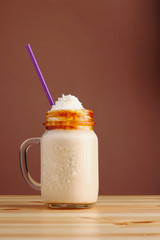 caramel frappucino milkshake with coffee on wooden table. Salted caramel ice cream sundae. Cold...