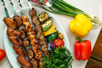 assorted of kebabs with grilled vegetables, pickled onions, herbs and spicy sauce