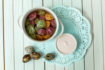rainbow dumplings for children on a wooden background with flowers and quail eggs