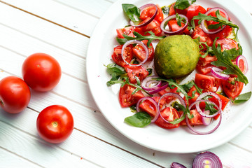 salad with baked mozzarella cheese with onions and tomatoes on a wooden surface