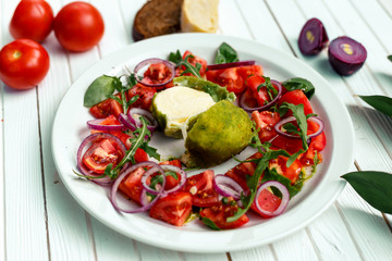 salad with baked mozzarella cheese with onions and tomatoes on a wooden surface