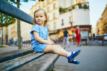 Two year old girl sitting on the bench in Paris, France