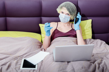 self-isolation and work at home with covid-19 coronavirus. a girl in protective gloves, a mask and...