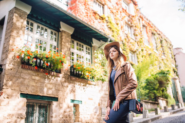 A beautiful young woman in a brown jacket walks in the early morning on the famous Montmartre hill in Paris