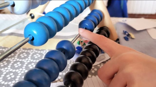 Close up of primary school kid using abacus for math homework on excercise book,home family