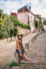 A beautiful young woman in a brown jacket walks in the early morning on the famous Montmartre hill...