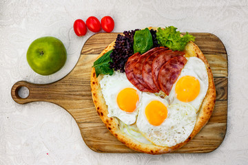 Bacon and eggs on a wheat cake with greens for lunch