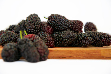 Black mulberry stack on white background on bamboo board