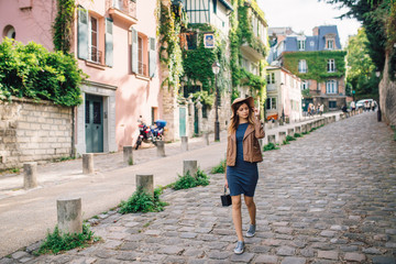 A beautiful young woman in a brown jacket walks in the early morning on the famous Montmartre hill...