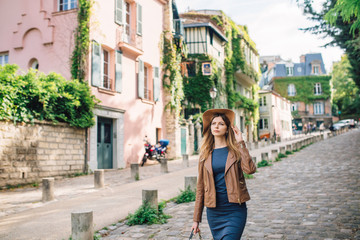 A beautiful young woman in a brown jacket walks in the early morning on the famous Montmartre hill...