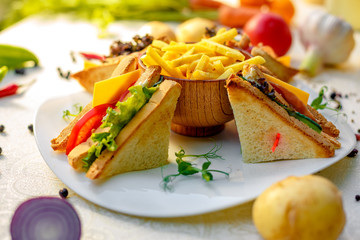 sandwiches with fresh vegetables and chicken with fried potatoes on a white tablecloth