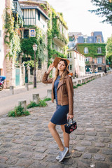 A beautiful young woman in a brown jacket walks in the early morning on the famous Montmartre hill...