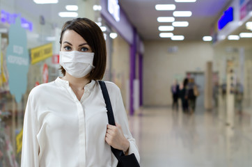  A woman in a medical mask on her face protecting from coronavirus is talking on the phone. Conservation concept from Covid-19.