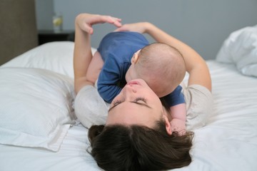 Young mother and baby together at home lying in bed, view from above