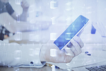 Double exposure of man's hand holding and using a digital device and data theme hologram drawing. Technology concept.