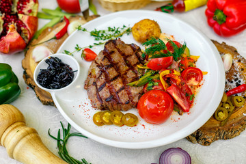 BBQ, juicy steak with grilled vegetables and sauce on a white plate