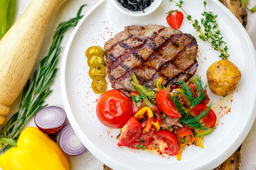 BBQ, juicy steak with grilled vegetables and sauce on a white plate