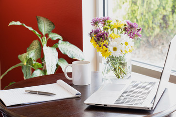 cup of coffee and computer on the table with flowers