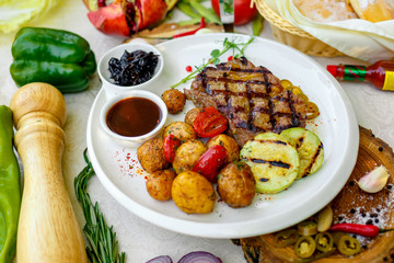 BBQ, juicy steak with grilled vegetables and sauce on a white plate