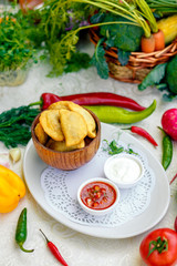 pies with meat in wooden utensils with sauces on a white plate