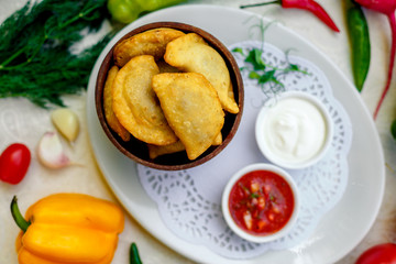 pies with meat in wooden utensils with sauces on a white plate