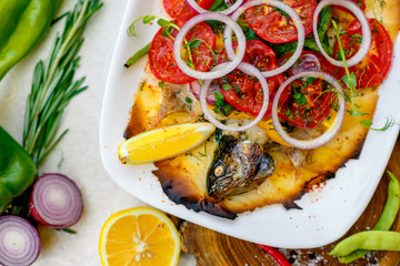 hot smoked fish koktal, Kazakh dish, with vegetables, tomatoes and onions on a festive table, special dish
