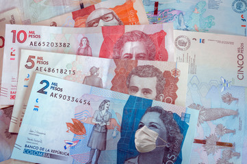 Close up of two five ten and twenty thousand Colombian pesos banknotes with face masks symbolizing the concept of the financial crisis in Colombia due to the covid-19 coronavirus. Colombian money