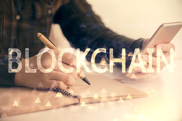Double exposure of blockchain business sketch hologram and woman holding and using a mobile device.