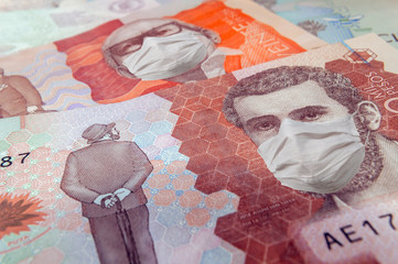 Close up of a five and twenty thousand Colombian peso bill with face masks symbolizing the concept of the financial crisis in Colombia due to the covid-19 coronavirus. Colombian money