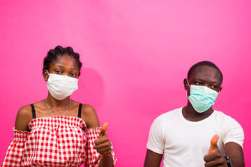 closeup of two africans wearing face mask isolated over pink background preventing, prevent,...