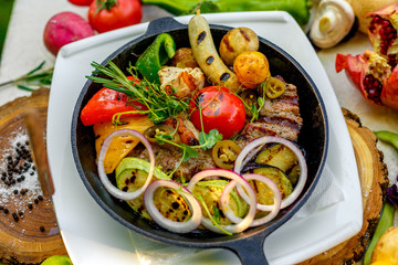 fried meat on the frying pan with vegetables and baked potatoes with vegetables