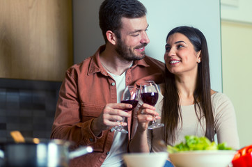 Cute couple drinking wine in the kitchen while preparing dinner