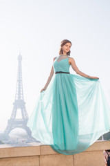 Obraz premium a girl in Paris in a green dress against the backdrop of the Eiffel tower elegant on the Trocadero square in summer a luxurious beautiful figure