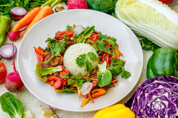 Thai meat with vegetables on a decorated table in a white plate
