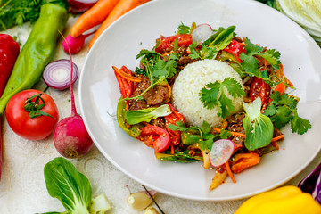 Thai meat with vegetables on a decorated table in a white plate
