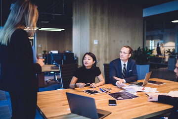 Diverse colleagues teamworking on project ideas sitting at desk with modern technology, intelligent multiracial partners brainstorming for cooperation and discussing ideas in office interior