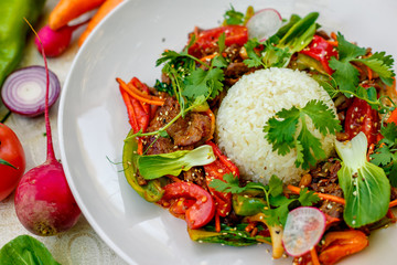Thai meat with vegetables on a decorated table in a white plate