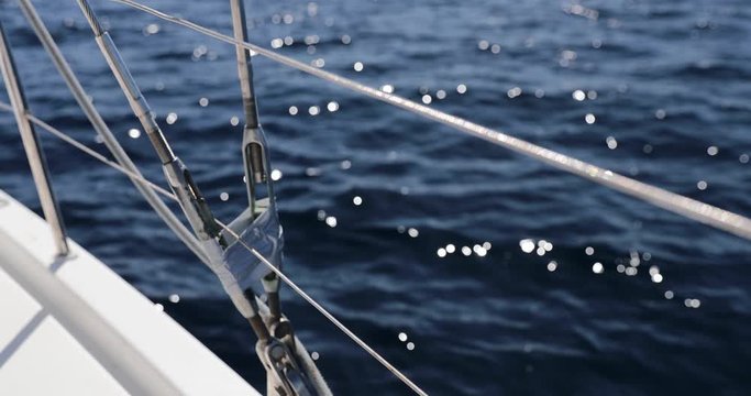 Close-up view of sailboat metal cable at sunny weather, pulleys and ropes on the mast, yachting sport, ship equipment, sea is on background