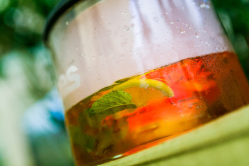 Close-up. Lemon and mint are floating in the brewed tea in a glass teapot.